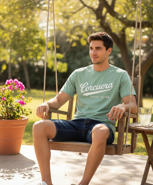 Man sitting on a swing in a garden wearing a green t-shirt with 'Cercuera' branding.